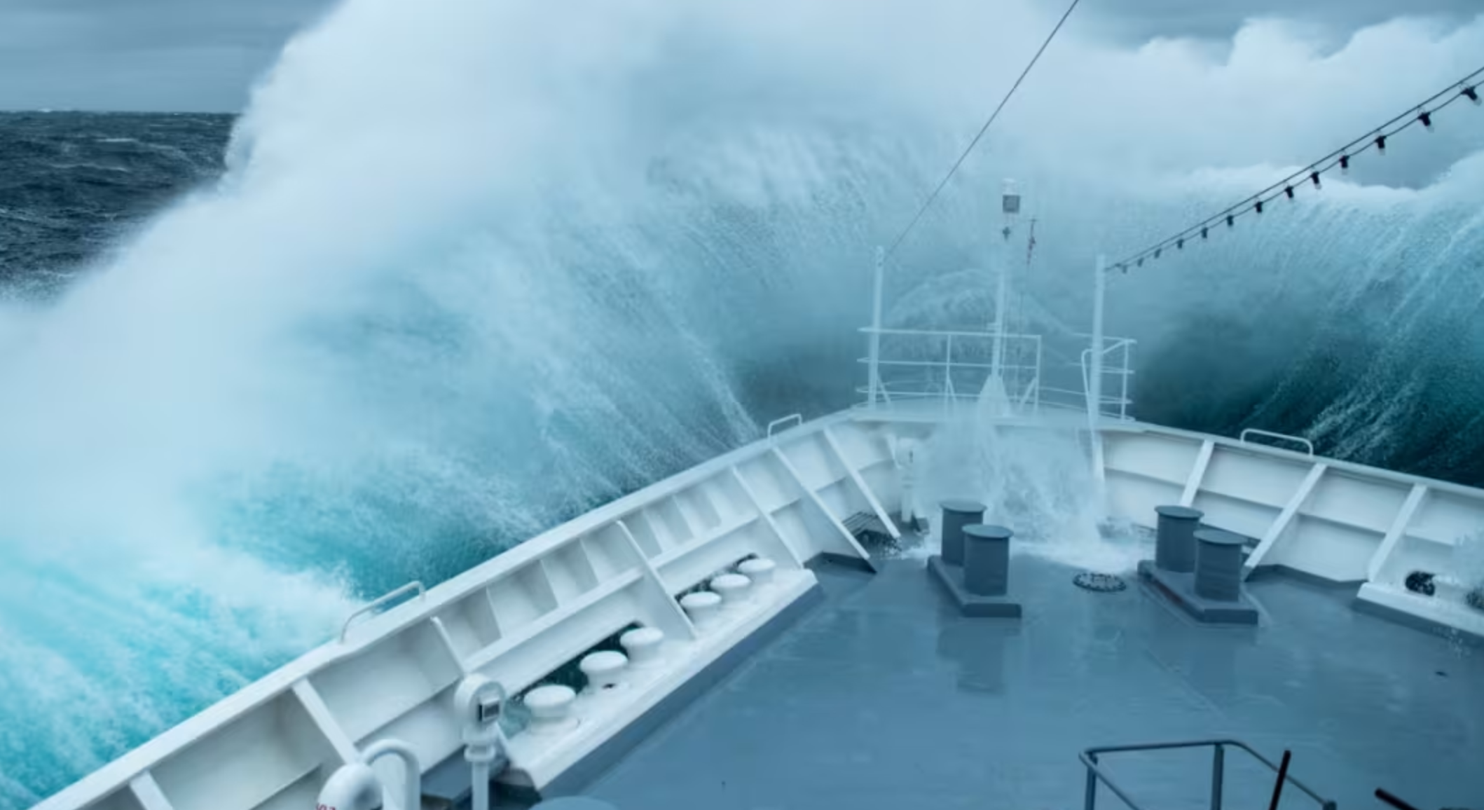 Man in hard hat on a ship deck overlooking ocean.